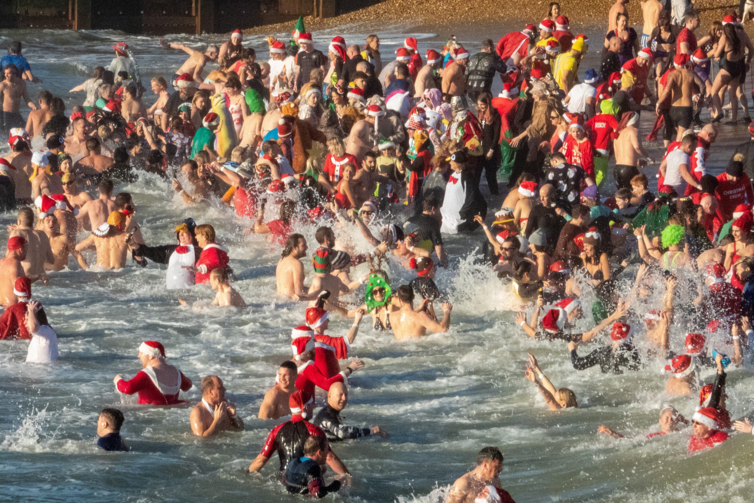People swimming in the sea wearing Santa hats