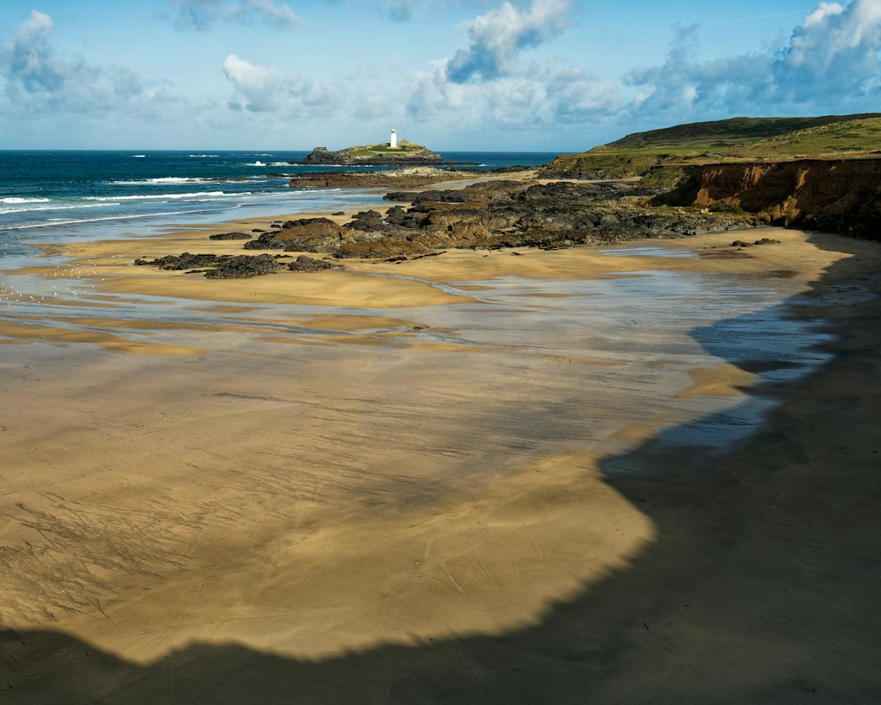 Coastal beach and rocks and lighthouse at Godrevy