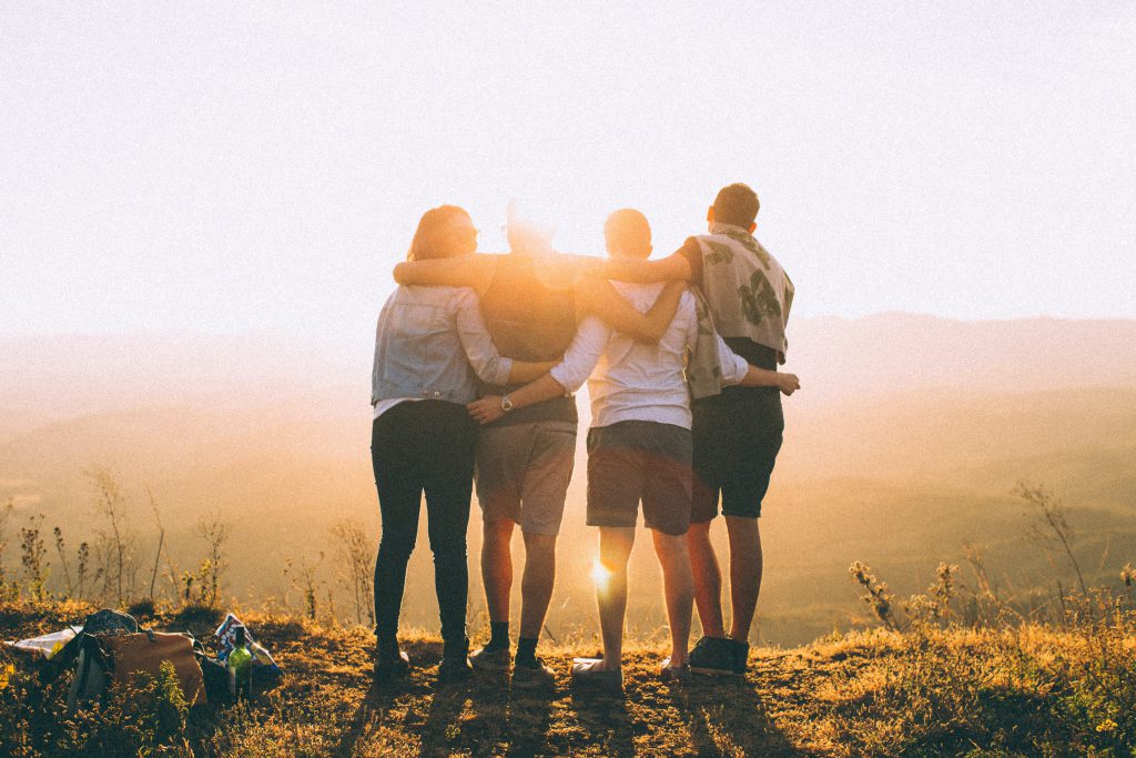 group of four friends hugging in the sunset