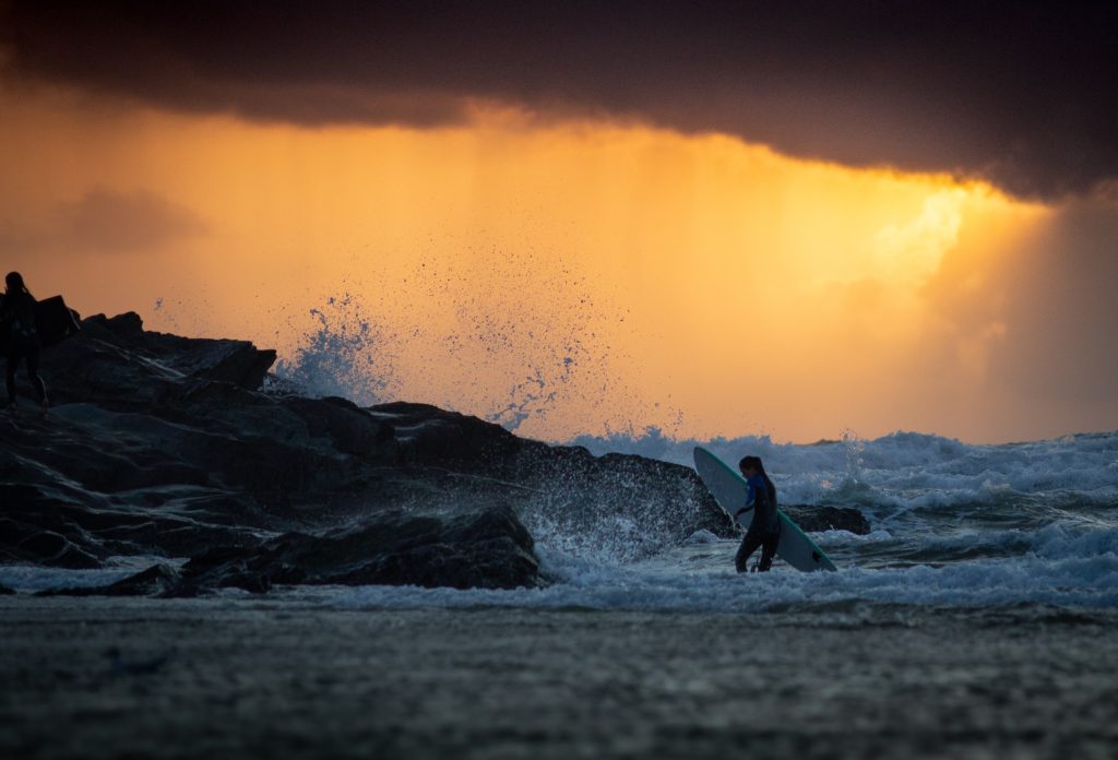 a surfer exiting the water at sunset