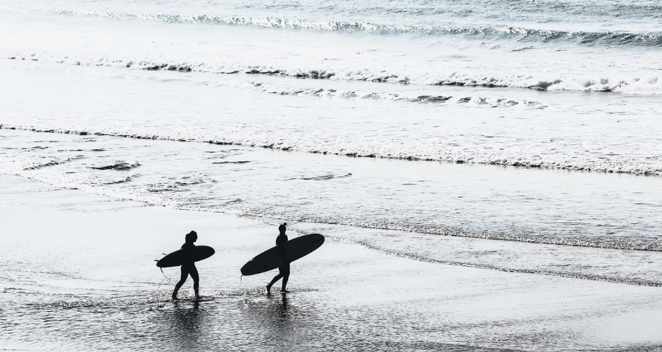 two surfers walking on the beach